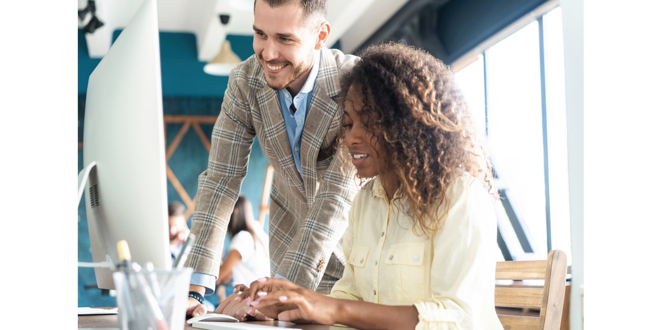 African American businesswoman types away as her male colleague looks on her screen